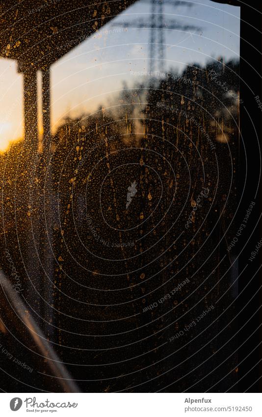 Perspective endangered Window polish Window pane Dirty Rain Glass Sunset Slice Drops of water Living or residing Weather Vantage point Electricity pylon Tracks