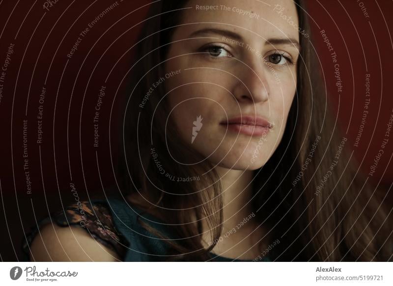 Close up portrait of young brunette woman with off shoulder sweater sitting in front of red wall Face Face of a woman Woman Young woman pretty daintily Brunette