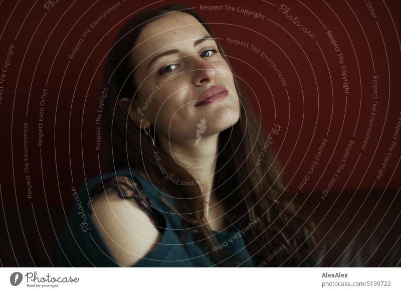 Close up portrait of young brunette woman with off shoulder sweater sitting in front of red wall Face Face of a woman Woman Young woman pretty daintily Brunette