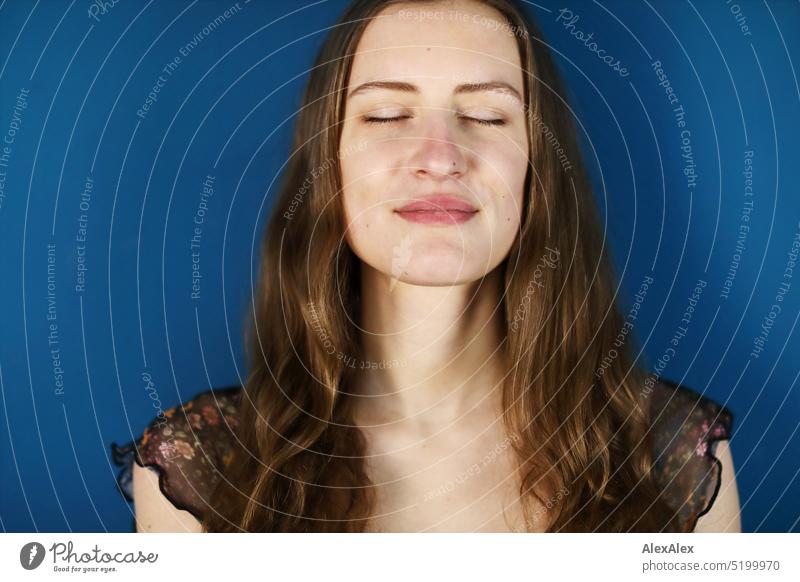 Close portrait of young brunette woman in front of petrol / blue green wall with smile and closed eyes Face Face of a woman Woman Young woman pretty daintily