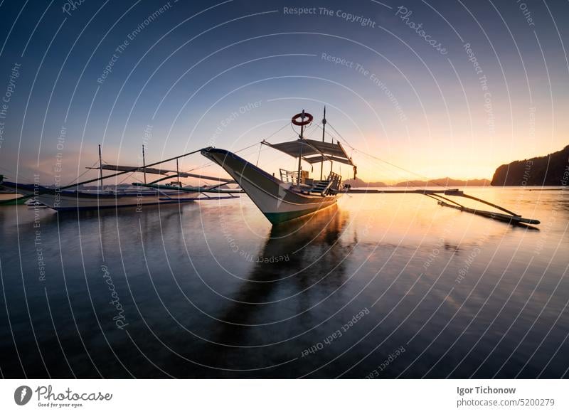 Tropical harbor bay in evening. Golden hour in lagoon in Philippines, Palawan, El Nido. Sunset on beach. Tranquil scenic sundown above mountains islands on horizon