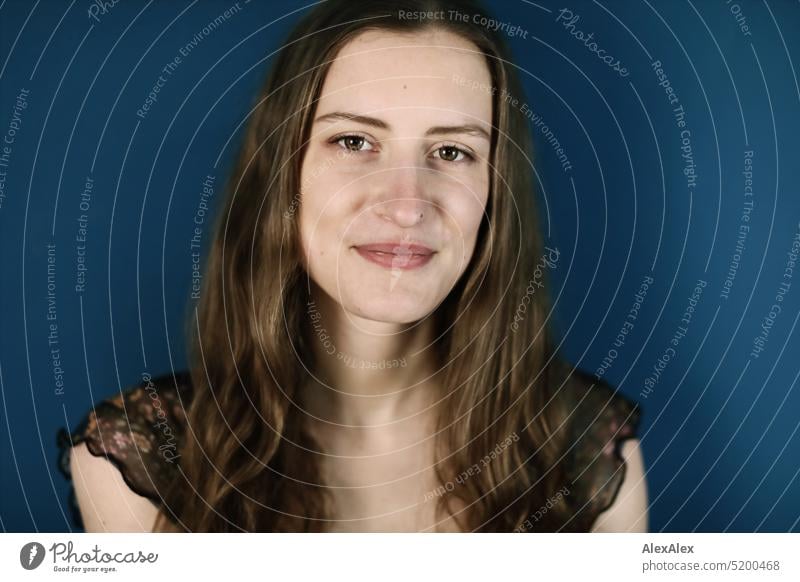 Close portrait of young brunette woman in front of petrol / blue green wall Face Face of a woman Woman Young woman pretty daintily Brunette Bright Adults