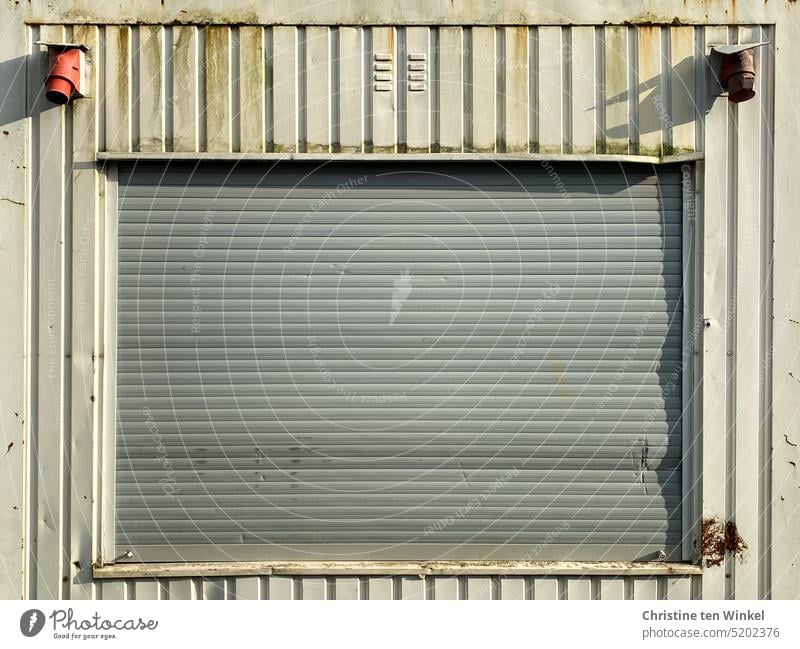 Closed roller shutter of a construction container in sunlight Roller shutter Window Old worn-out Sunlight Construction site Container office container frowzy