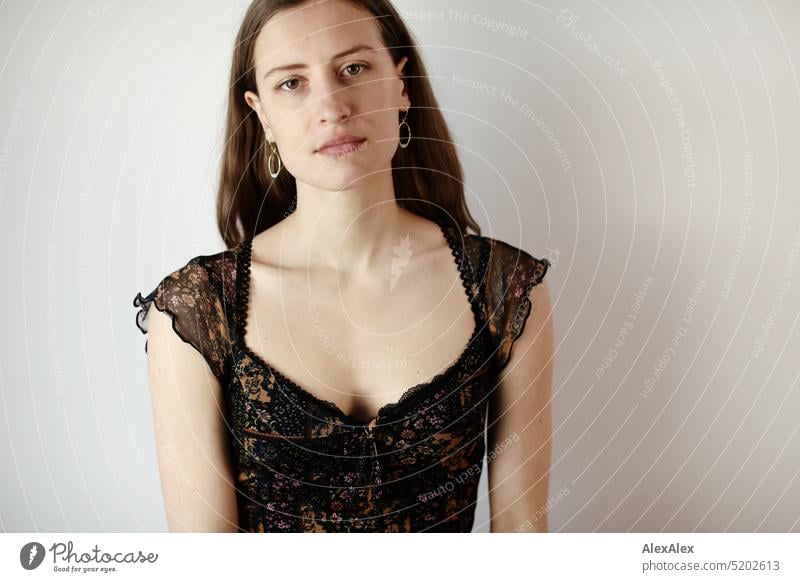 Portrait of a young brunette woman in a dark summer dress in front of a white wall Face Face of a woman Woman Young woman pretty daintily Brunette Bright Adults