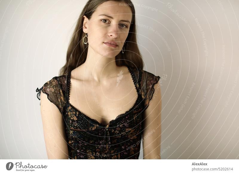 Portrait of a young brunette woman in a dark summer dress in front of a white wall Face Face of a woman Woman Young woman pretty daintily Brunette Bright Adults