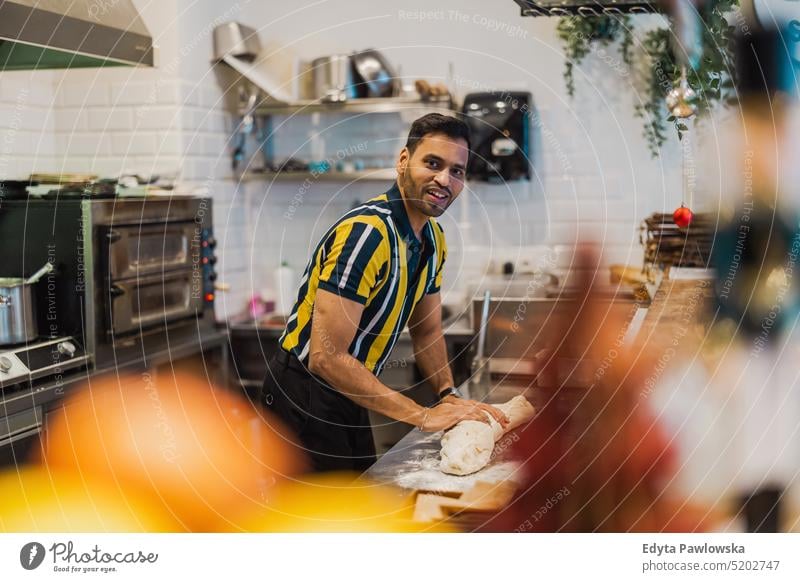 Young man preparing fresh food in commercial kitchen occupation owner young person employee professional job indian man asian catering making cooking vegan