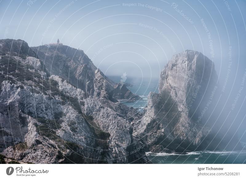 Rocky coastline of Praia Da Ursaa in morning fog, Sintra, Portugal. Giant sea stacks towering up along atlantic ocean coast. Holiday travel vacation season