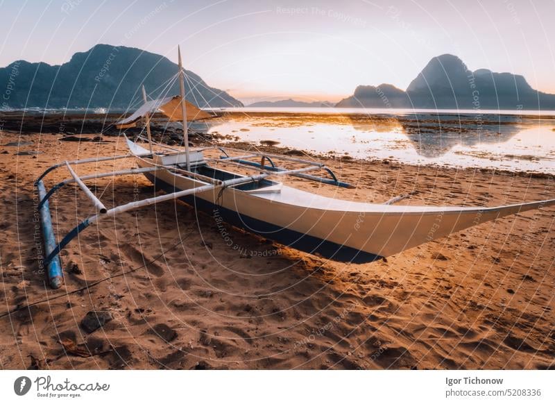 Boat on the beach in El Nido bay. Beautiful scenery with ocean lagoon in sunset light, Palawan, Philippines travel vacation philippines twilight el nido shallow