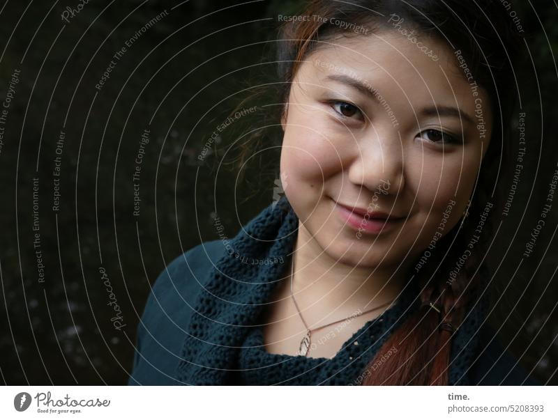 Woman in half light, smiling kind Dim Face portrait contented left Feminine Intensive Jewellery out Smiling close Looking into the camera Esthetic Smooth