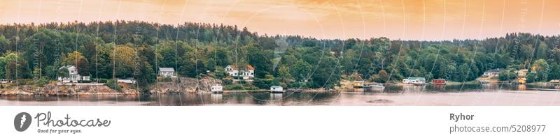 Sweden. Many Beautiful Swedish Wooden Log Cabins Houses On Rocky Island Coast In Summer Evening. Lake Or River Landscape. Panorama, Panoramic View. panorama