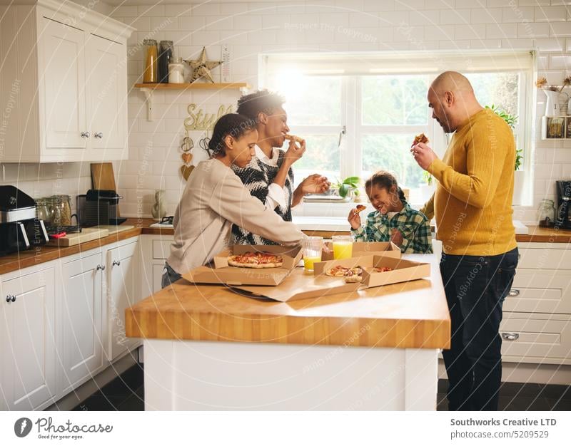 Family with boy with Down syndrome enjoying takeaway pizza for dinner family down syndrome enjoyment eat multiracial meal food excitement hungry box takeout