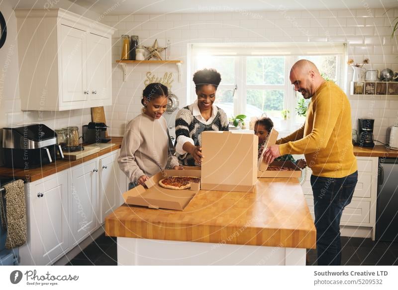 Family serving takeaway pizza for dinner in kitchen family takeout serve enjoyment eat multiracial meal food excitement hungry box lunch down syndrome