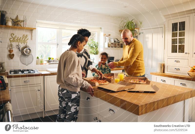 Family with boy with Down syndrome enjoying takeaway pizza for dinner family takeout home multiracial meal food down syndrome excitement hungry box lunch