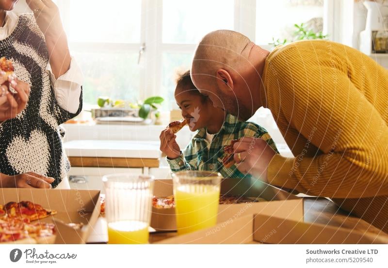 Boy with Down syndrome enjoying takeaway pizza with family boy down syndrome eat father dinner enjoyment multiracial smile cheerful happy laugh fun meal food