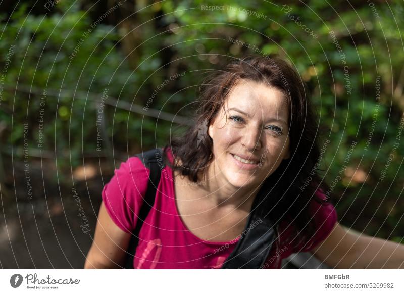 Woman with sweaty hair laughs happily into camera Sweaty Brunette Laughter fortunate look up Hiking hike Effort Attractive pretty Smiling rays pleased Joy