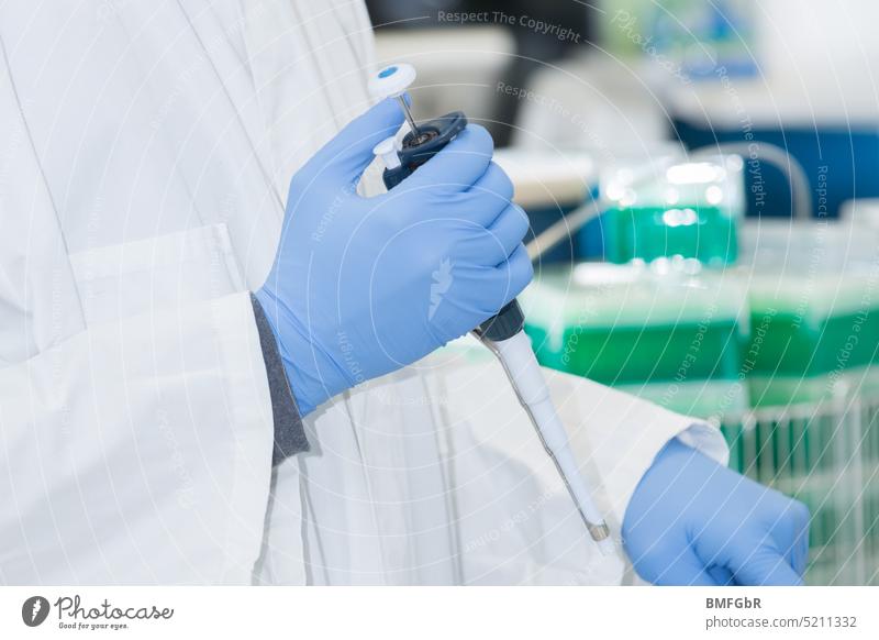 Laboratory worker pipetting with pipette Pipette Employees &amp; Colleagues Laboratory staff Laboratory gloves Blue Science & Research Biology Technology