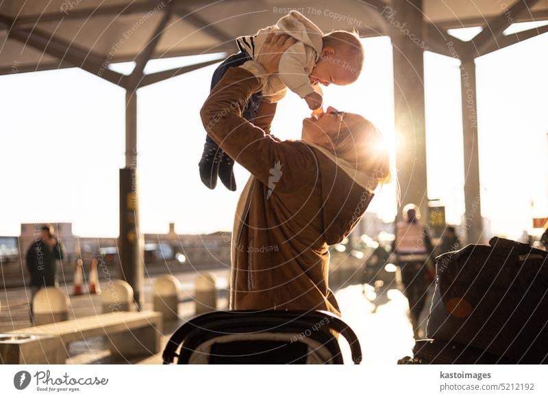 Motherat happily holding and lifting his infant baby boy child in the air after being rejunited in front of airport terminal station. Baby travel concept. love