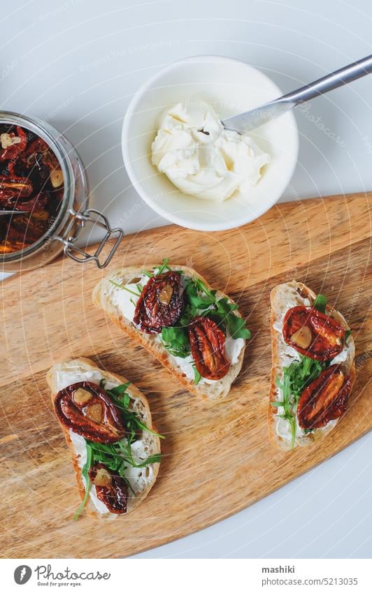 italian traditional bruschetta - bread toast with sun dried tomatoes, cream cheese, olive oil and arugula. sandwich food snack vegetable healthy herb appetizer