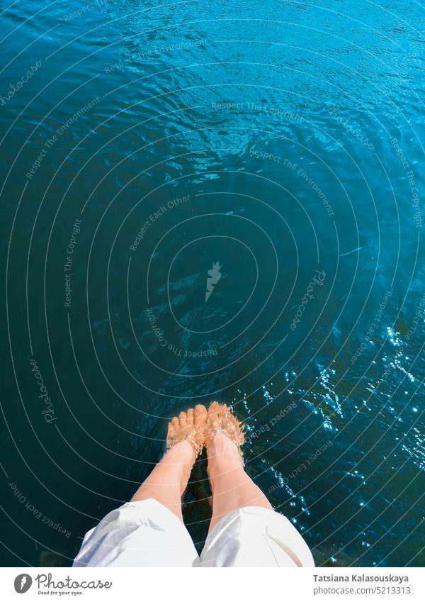 A woman lowered her feet into turquoise seawater vacation beach travel blue legs foot tourism relax person holiday female summer ocean women swimming pool