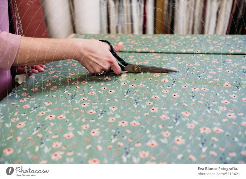 senior woman working in atelier shop with rolls of fabrics. Cutting fabrics. Small business small business ironing job entrepreneur crafts denim profession