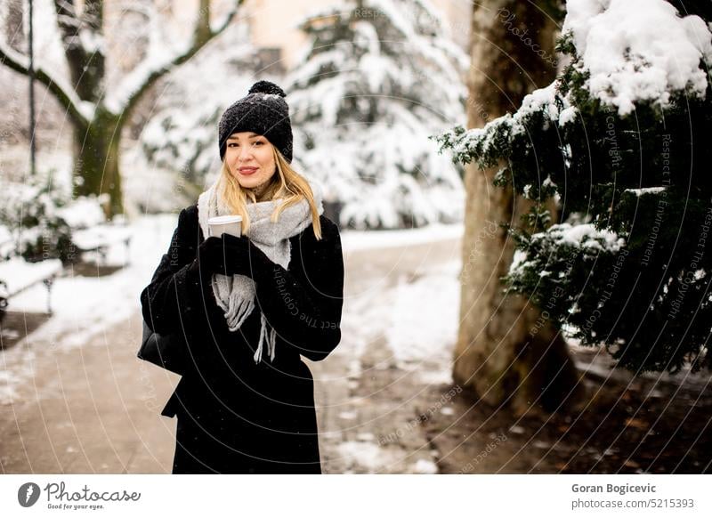 Young woman in warm clothes enjoying in snow with takeaway coffee cup adult air alone beautiful beauty brunette cap charming coat cold cute day emotions female