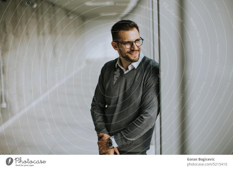 Young modern businessman standing in the office corridor beard biusiness man company corporate employee eyeglasses financial handsome happy indoors job