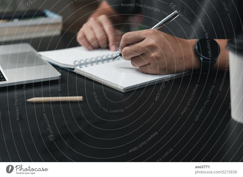 man hands with pen writing on notebook in the office.learning, education and work.writes goals, plans, make to do and wish list on desk. content script