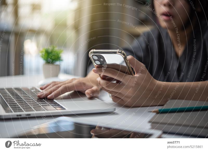 woman working on laptop computer and using mobile phone on desk digital technology concept. business people office online smart person smartphone communication