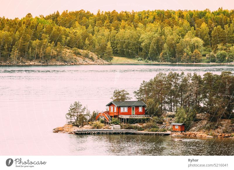 Sweden. Many Beautiful Red Swedish Wooden Log Cabin House On Rocky Island Coast In Summer. Lake Or River Landscape sweden house huts hygge travel nature