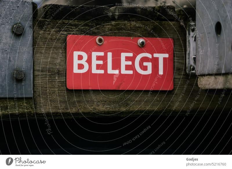 Red sign with the words 'Occupied' on a wooden plank Coated Colour photo Wood planks iron mount Deserted Exterior shot Detail Footbridge Signs and labeling