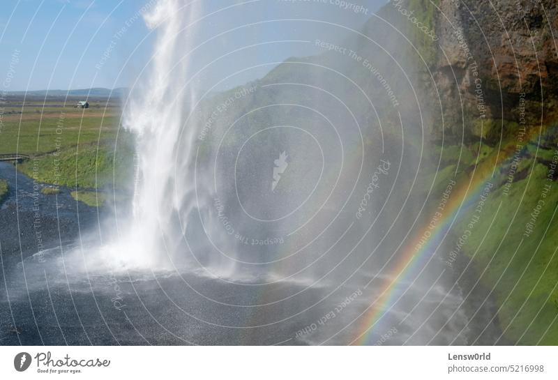 A rainbow in front of Seljalandsfoss waterfall on the southern coast of Iceland on a sunny day beautiful cascade environment flow green iceland landscape