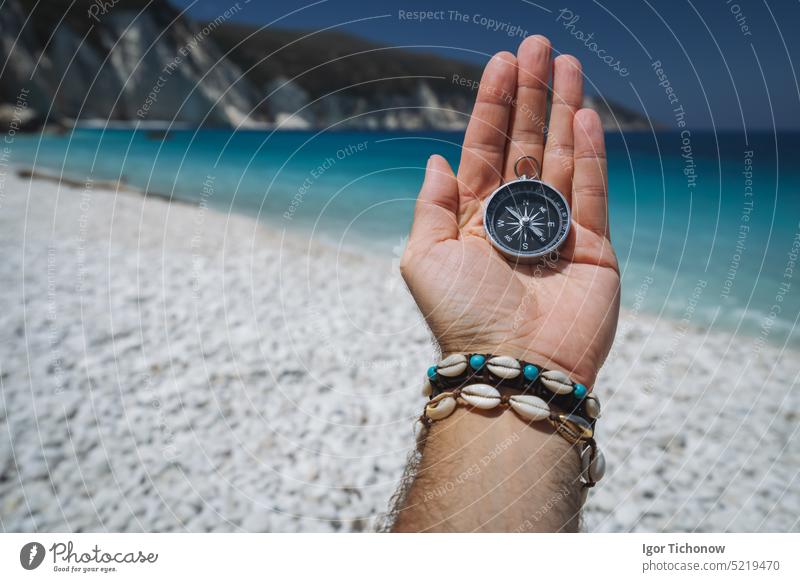 Hand holding a compass on the beach in background hand sea vacation travel equipment lost journey summer east hiking exploration direction guidance ocean