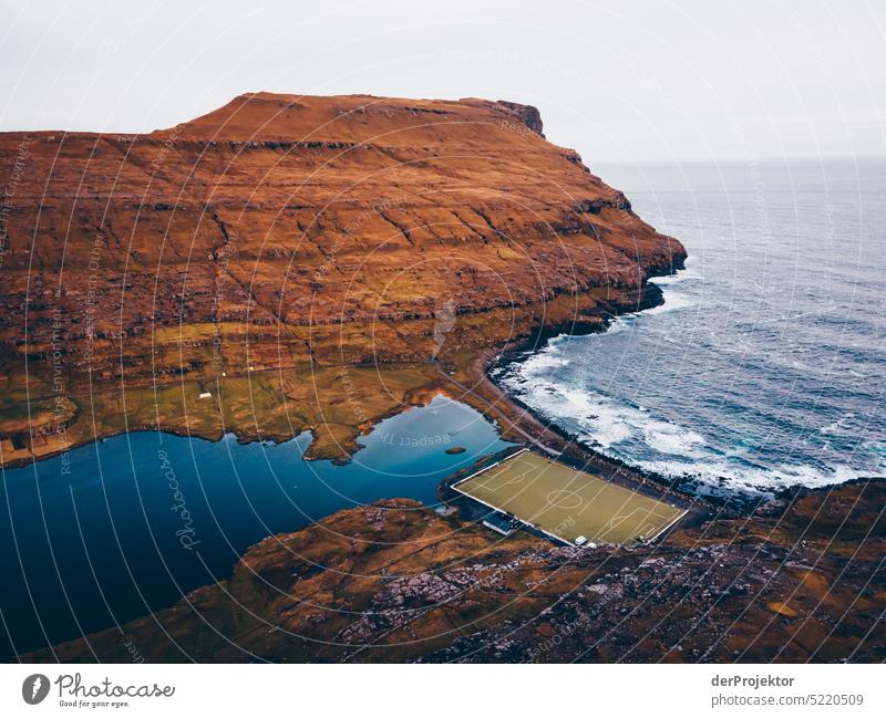 View of soccer field with landscape Street rocky Bad weather Environment Hill Rock highlands Rural harmony Weather Picturesque Faroe Islands Sunlight