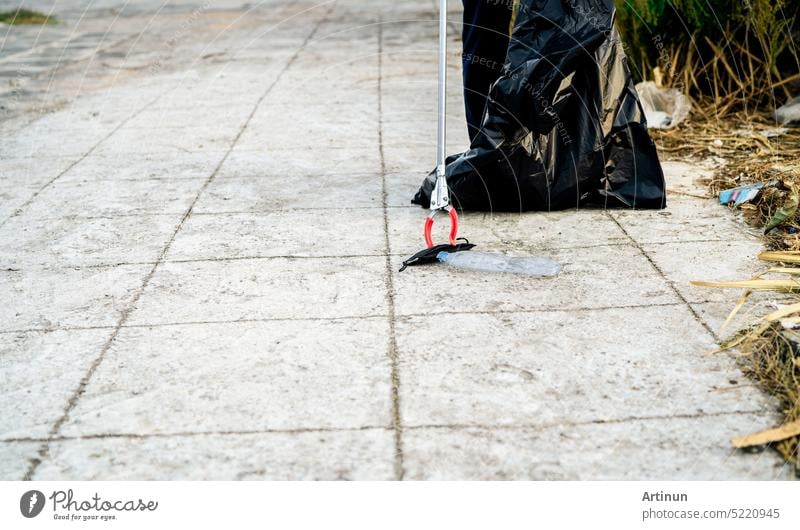 Volunteer collecting used medical face mask near plastic bottle into trash plastic bag for cleaning urban street. Clean up community garbage. World environment day, save the earth. Medical waste.