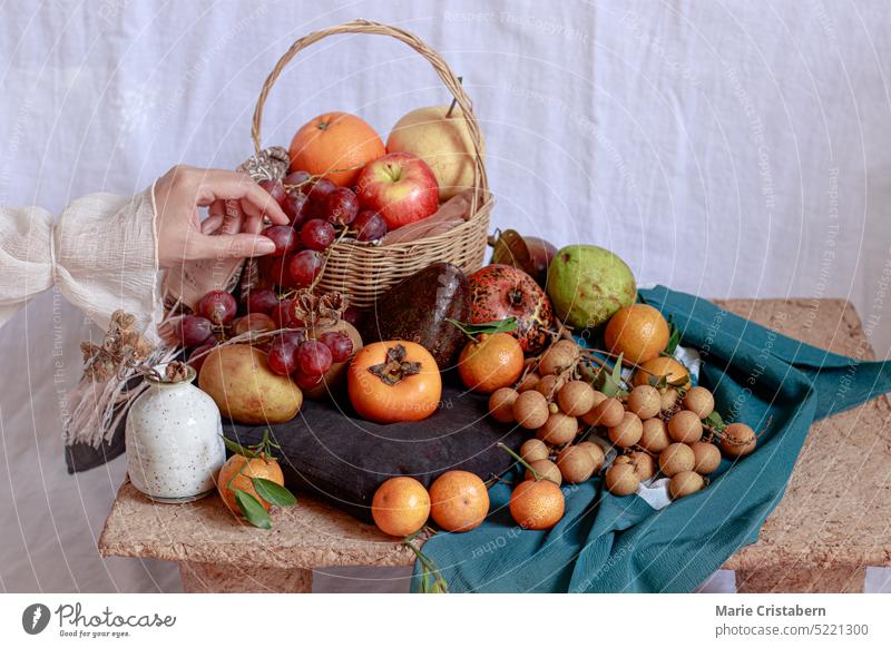 Dainty hand holding a grape over a table filled with bountiful fresh fruits dainty concept springtime bounty produce healthy lifestyle peaceful romantic calm