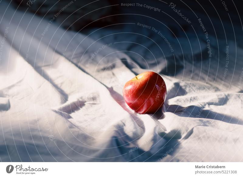 Conceptual still life of an apple on an unmade bed showing concept of springtime, mental health and slow living still-life minimalism copy space nobody