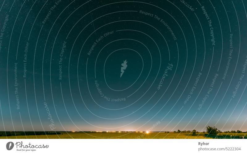 Night Starry Sky Above Summer Field Meadow With Blooming Rapeseed. Glowing Stars And Sunset Sunrise Lights Above Meadow Landscape. sky background cosmic star