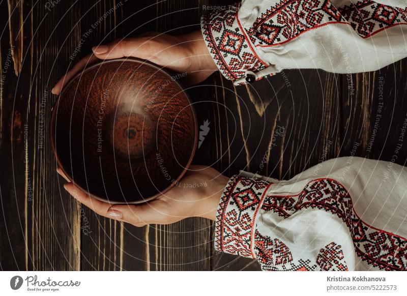 Female hands with empty ukrainian clay bowl on wooden table. Copy space. antique brown ceramic ceramics clay plate clay pottery color colorful copy space