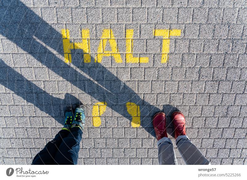 HALT in yellow capital letters calls for stopping and looking Hold upper-case letters Yellow Street Paving stone Cobbled pathway Road traffic feet