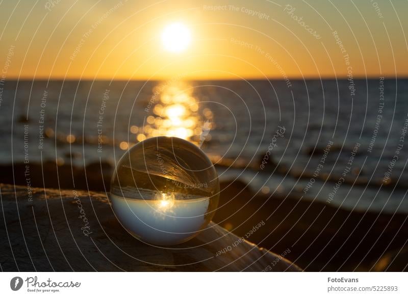 Ball made of glass lies on a stone in which the beach and the sea are reflected View Climate nature water ball land lensball quiet Weather ocean Glass ball