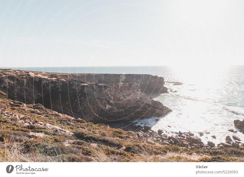 Breathtaking cliffs with a pebble beach in the afternoon sun on the Atlantic coast at Vila Nova de Milfontes, Odemira, Portugal. In the footsteps of Rota Vicentina. Fisherman trail