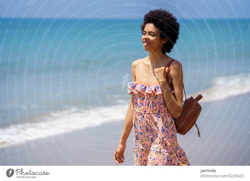 Young ethnic female spending summer vacation on seashore woman explore sand beach ripple ocean recreation young black colorful smile toothy smile happy cheerful