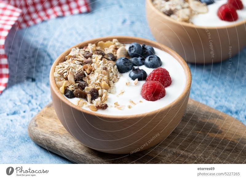 Yogurt with berries and muesli for breakfast in bowl on blue background yogurt blueberry raspberry fruit nuts cereals greek dairy raisins healthy food wooden