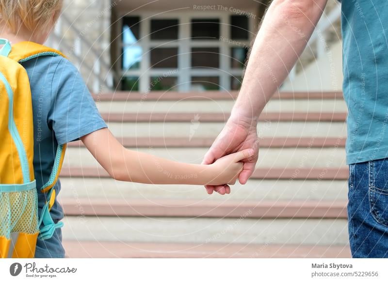 Little schoolboy with his father goes to school after summer holiday. Parent accompanies or meets the child. Quality education for children. back student