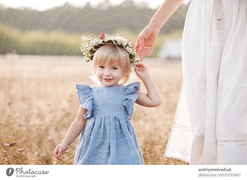 Young mother walking with her little daughter in the gold field. Family holiday in garden, park. Portrait mom with child together on nature. Mum, little daughter outdoors. Happy Mothers Day. Close up