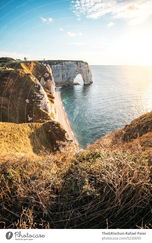 Coast with rocks and sea in sunset Pebble beach France Normandie Étretat Moody evening mood Clouds Ocean Rock cliffs Landscape Nature coast Exterior shot