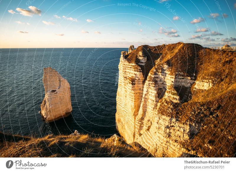 Coast with rocks and sea in sunset Pebble beach France Normandie Étretat Moody evening mood Clouds Ocean Rock cliffs Landscape Nature coast Exterior shot