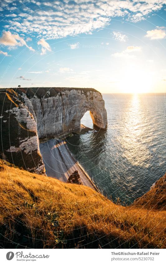 Coast with rocks and sea in sunset Pebble beach France Normandie Étretat Moody evening mood Clouds Ocean Rock cliffs Landscape Nature coast Exterior shot