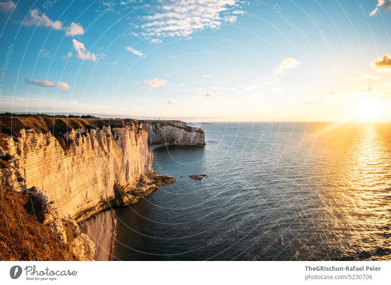 Coast with rocks and sea in sunset Pebble beach France Normandie Étretat Moody evening mood Clouds Ocean Rock cliffs Landscape Nature coast Exterior shot