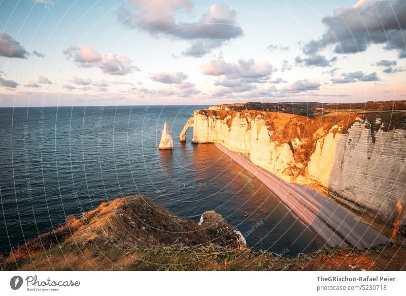 Coast with rocks and sea in sunset Pebble beach France Normandie Étretat Moody evening mood Clouds Ocean Rock cliffs Landscape Nature coast Exterior shot